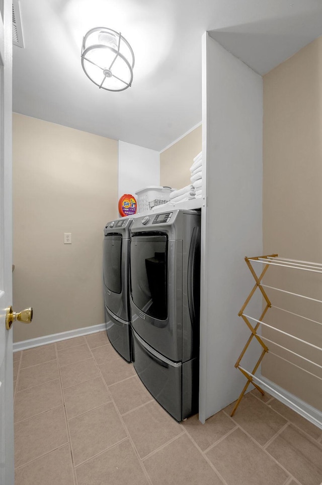 laundry room featuring light tile patterned floors, baseboards, visible vents, laundry area, and separate washer and dryer