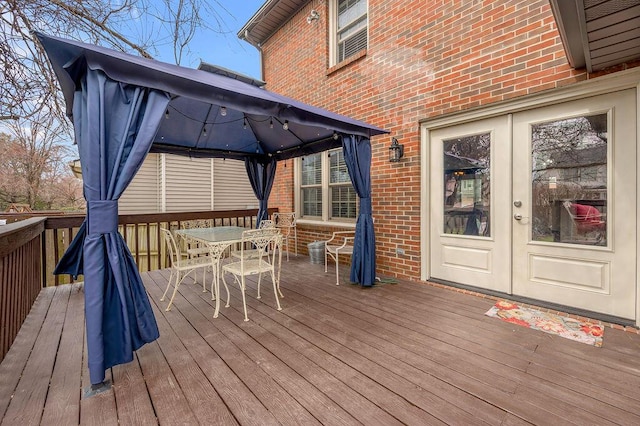 wooden terrace featuring a gazebo, french doors, and outdoor dining area