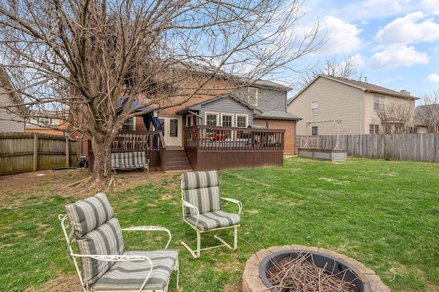 view of yard with a fenced backyard, a fire pit, and a deck