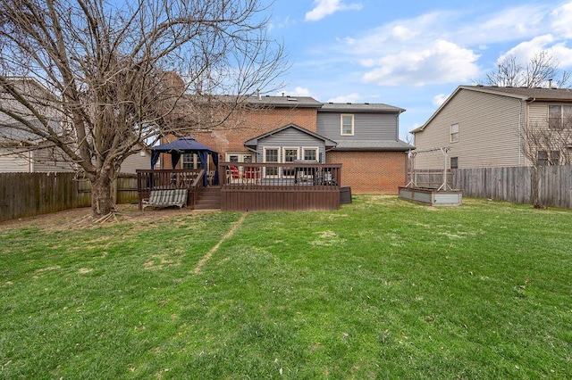 back of property featuring a deck, a fenced backyard, a gazebo, a yard, and brick siding