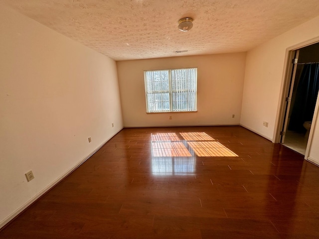 empty room featuring baseboards, a textured ceiling, and wood finished floors