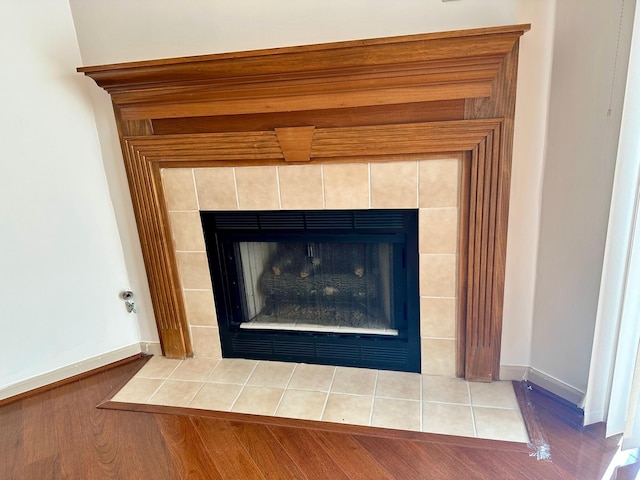 room details with wood finished floors, baseboards, and a tile fireplace