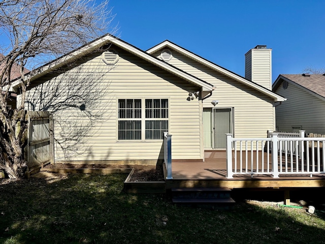 back of house featuring a lawn, a deck, and a chimney