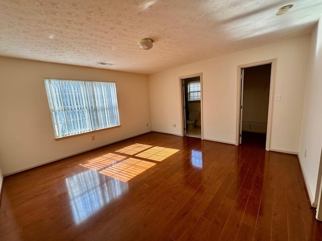 unfurnished room with baseboards, a textured ceiling, and wood finished floors