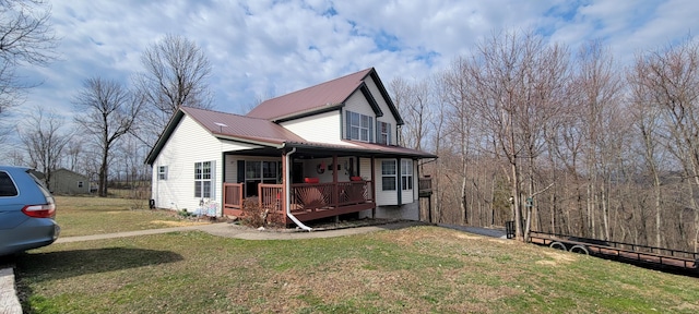 view of front of home featuring metal roof, a porch, and a front lawn