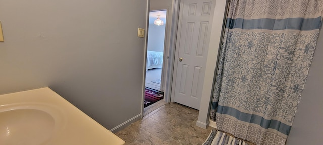 full bathroom with curtained shower, baseboards, and a sink