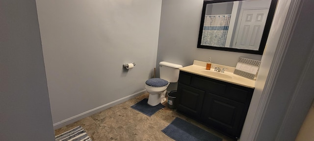 bathroom with baseboards, toilet, and vanity