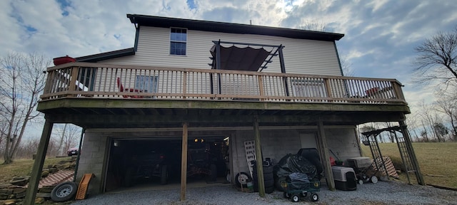 back of property with gravel driveway, concrete block siding, an attached garage, and a wooden deck