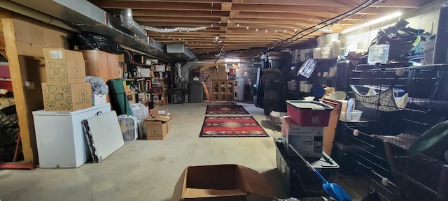 unfinished basement featuring refrigerator and electric water heater