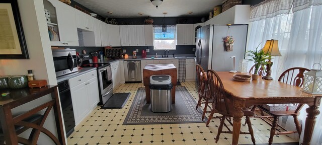 kitchen featuring a sink, stainless steel appliances, light floors, and white cabinetry