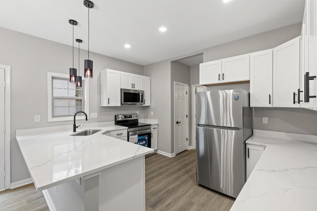 kitchen featuring a sink, light stone counters, stainless steel appliances, a peninsula, and white cabinets