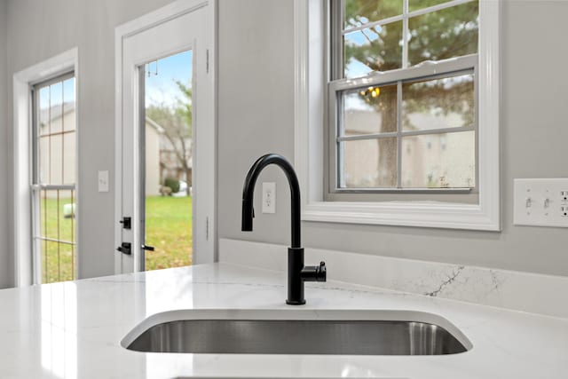 interior details with a sink and light stone counters