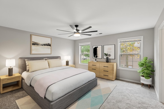 bedroom featuring visible vents, light colored carpet, a ceiling fan, and baseboards