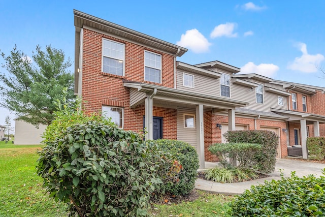 view of property with brick siding, an attached garage, concrete driveway, and a front yard