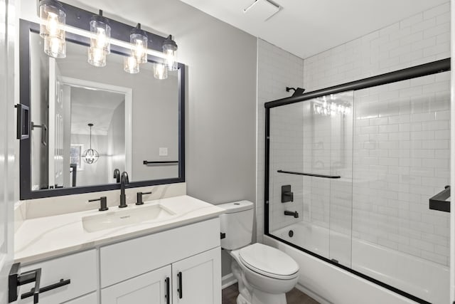 full bathroom featuring visible vents, toilet, vanity, and shower / bath combination with glass door