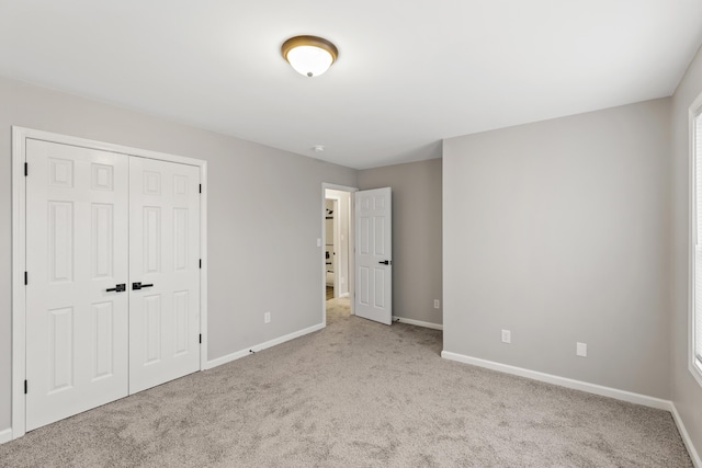 unfurnished bedroom with multiple windows, carpet flooring, baseboards, and a closet