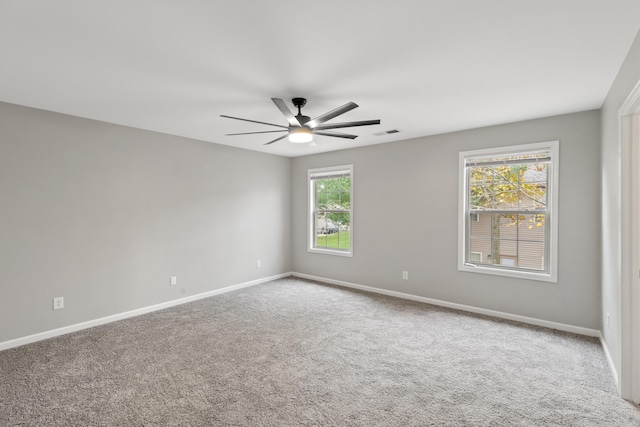 carpeted empty room featuring visible vents, a ceiling fan, and baseboards