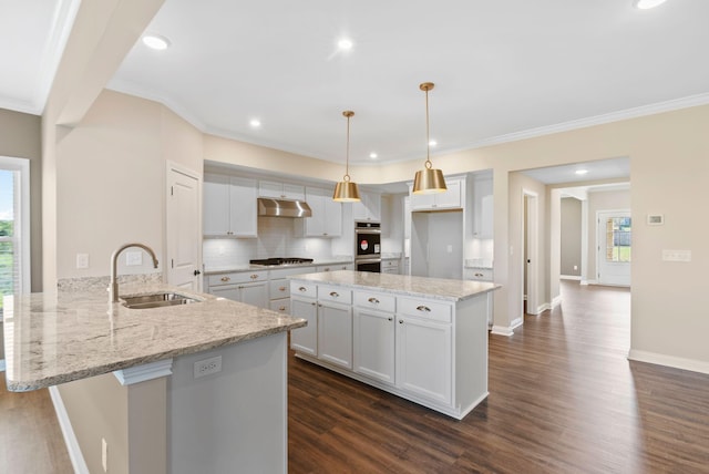 kitchen with under cabinet range hood, a sink, gas cooktop, double oven, and a peninsula