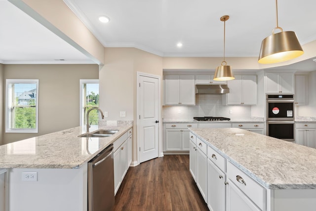 kitchen featuring a peninsula, a sink, under cabinet range hood, appliances with stainless steel finishes, and tasteful backsplash