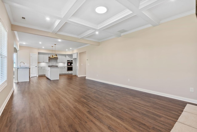 unfurnished living room with dark wood-style floors, baseboards, coffered ceiling, beam ceiling, and a sink