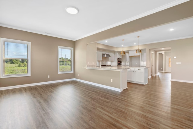 unfurnished living room with ornamental molding, wood finished floors, baseboards, and a sink