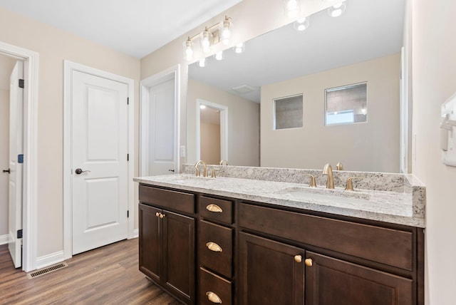 full bath with double vanity, visible vents, wood finished floors, and a sink