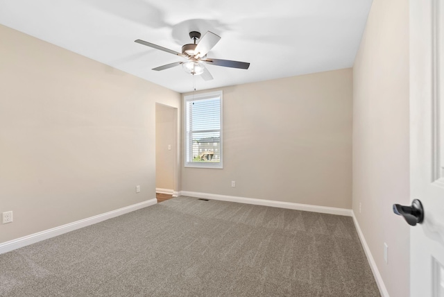 carpeted empty room with visible vents, baseboards, and ceiling fan