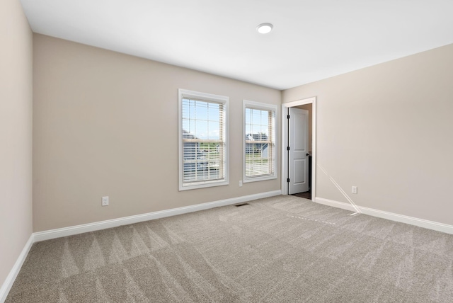 carpeted empty room featuring visible vents and baseboards