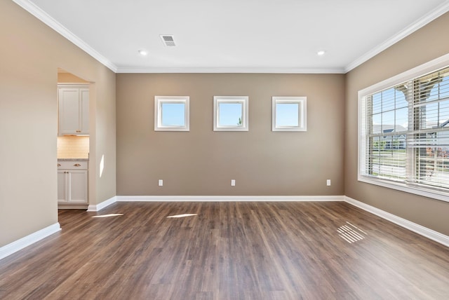 empty room featuring dark wood-type flooring, baseboards, and ornamental molding