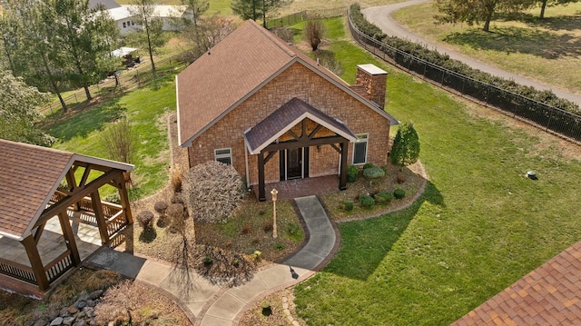 view of front of home featuring brick siding, a front lawn, roof with shingles, and fence