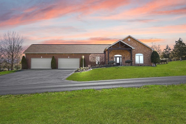 view of front of home featuring a garage, a front yard, and aphalt driveway