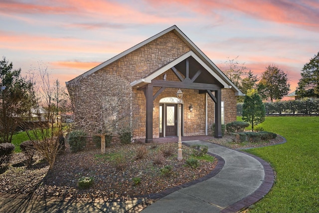 view of front of home with stone siding and a lawn