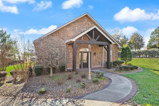 view of front facade with stone siding and a front lawn