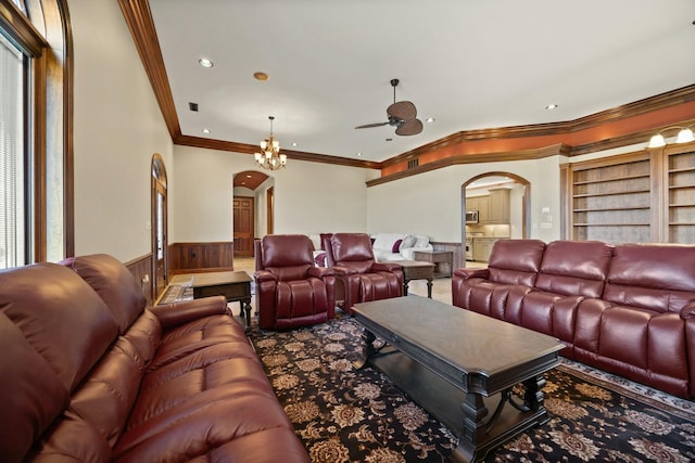 carpeted home theater featuring arched walkways, built in features, wainscoting, and ornamental molding