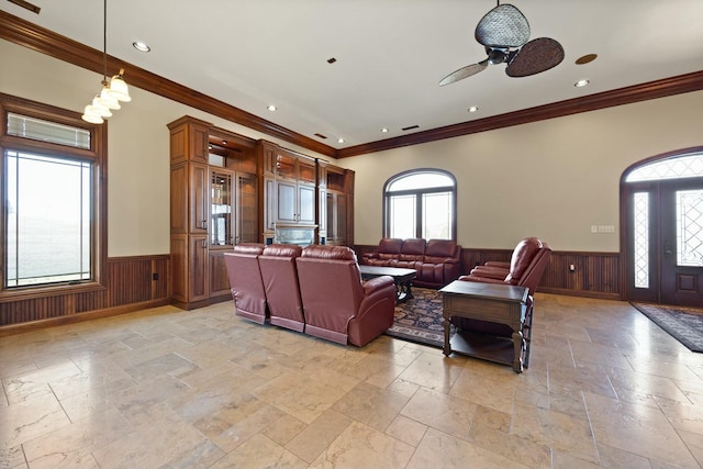 living area featuring a wainscoted wall, plenty of natural light, and stone tile flooring