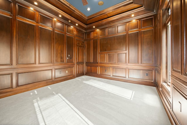 carpeted spare room featuring crown molding, a decorative wall, and wooden walls