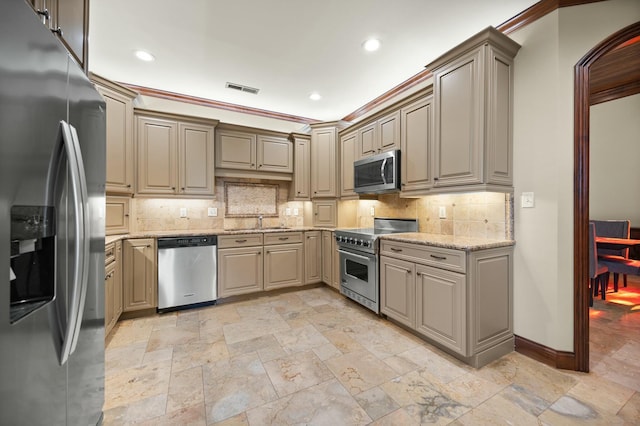 kitchen featuring visible vents, a sink, tasteful backsplash, stainless steel appliances, and light stone countertops