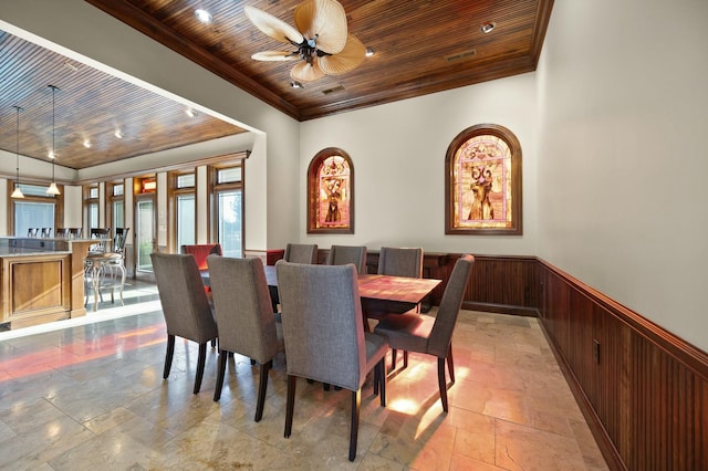 dining area with wood ceiling, ornamental molding, and wainscoting