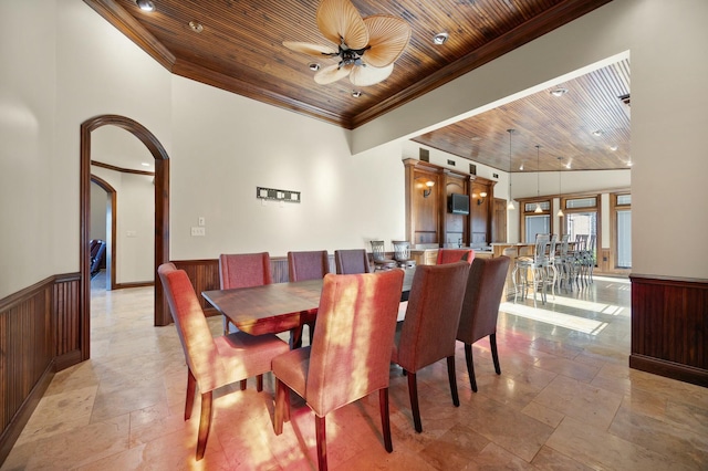 dining area featuring crown molding, ceiling fan, wood ceiling, wainscoting, and arched walkways