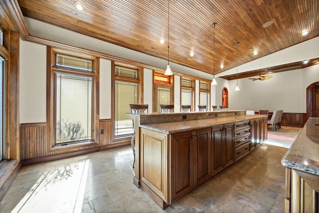 kitchen featuring decorative light fixtures, lofted ceiling, wainscoting, wooden ceiling, and arched walkways