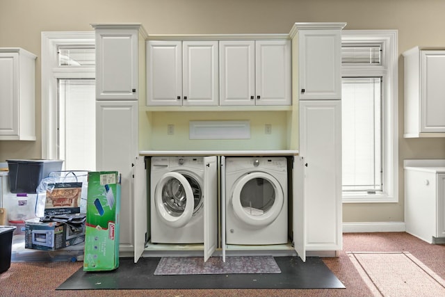 clothes washing area with baseboards, independent washer and dryer, and cabinet space