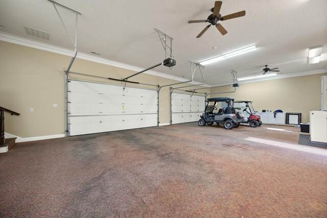 garage featuring visible vents, a ceiling fan, a garage door opener, and baseboards