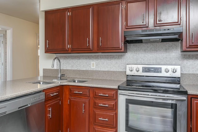 kitchen featuring light stone countertops, under cabinet range hood, decorative backsplash, appliances with stainless steel finishes, and a sink