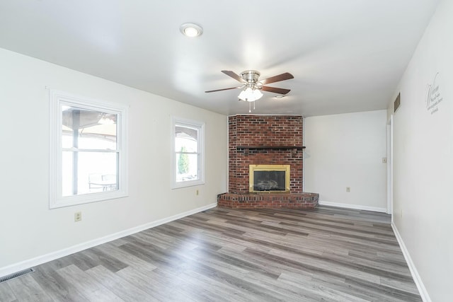 unfurnished living room featuring wood finished floors, a ceiling fan, visible vents, and baseboards