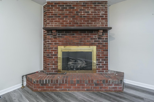 room details with baseboards, a brick fireplace, and wood finished floors