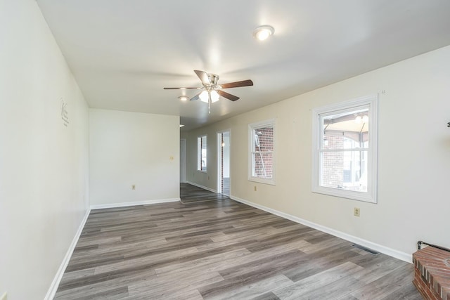 interior space with wood finished floors, a ceiling fan, visible vents, and baseboards