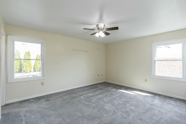 carpeted spare room featuring baseboards, visible vents, and ceiling fan