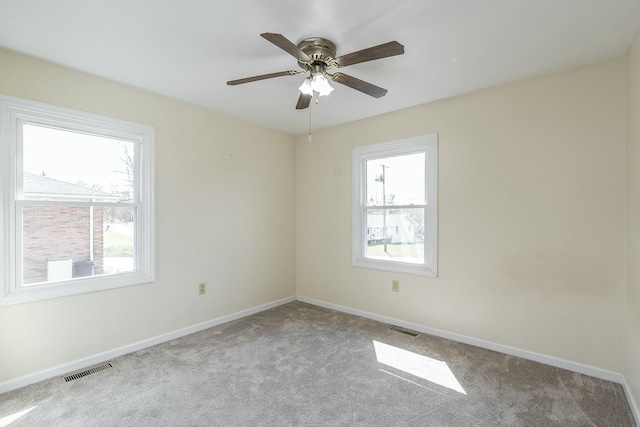 carpeted spare room featuring baseboards, visible vents, and ceiling fan