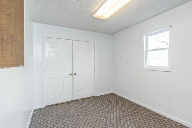 unfurnished bedroom with baseboards, carpet floors, a textured ceiling, and a closet