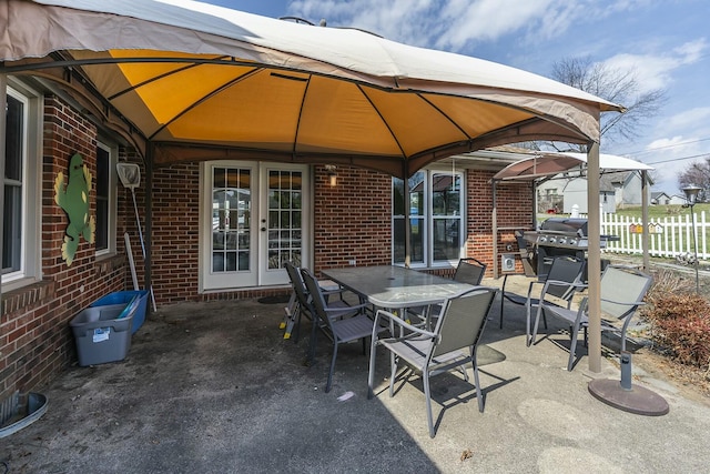view of patio with outdoor dining area, fence, french doors, and a grill